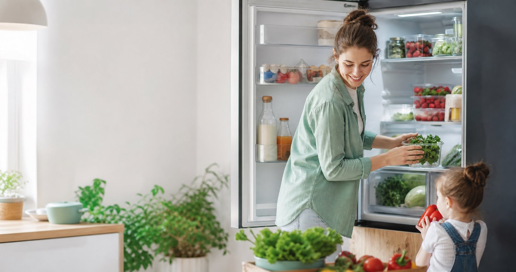 Молодая семья раскладывает свежие продукты в холодильнике